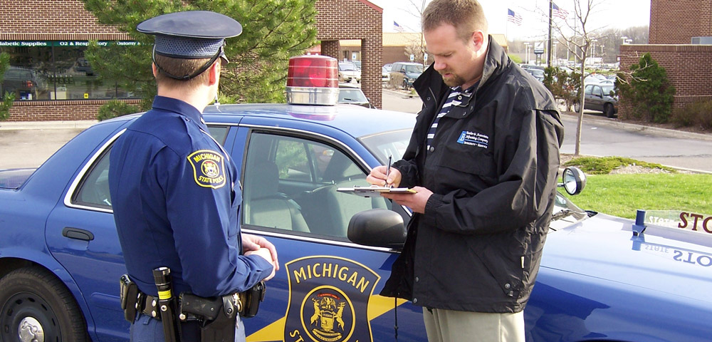 adjuster speaking with police officer while taking notes
